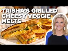 a woman standing in front of a plate with sandwiches on it and the words trisha's grilled cheesy veggie melts