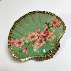 a green plate with pink flowers on it sitting on a white counter top next to a wall