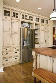 a large kitchen with an island in the middle and cabinets on both sides, along with a stainless steel refrigerator