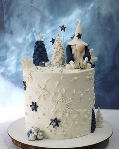 a white frosted cake decorated with snowflakes and trees