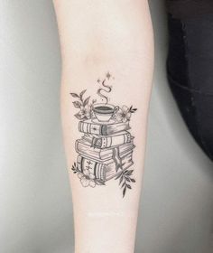 a person with a tattoo on their arm holding a coffee cup and stack of books