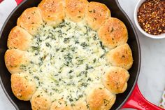 a skillet filled with spinach and cheese on top of a table next to other dishes