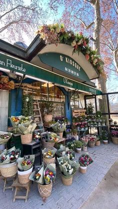 the flower shop has many baskets full of flowers in front of it and there are no people around