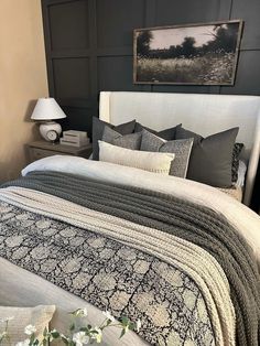 a bed with pillows and blankets on top of it next to a night stand filled with flowers