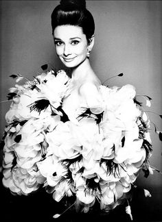 an old photo of a woman with flowers in her hair wearing a feathered dress