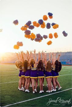 a group of cheerleaders standing on top of a field with their hands in the air