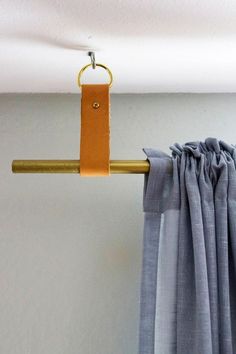 a curtain rod with a leather handle hanging from it's end, in front of a white wall