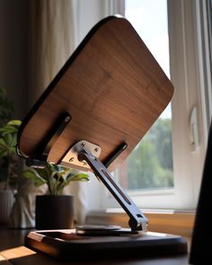 a wooden desk lamp sitting on top of a table next to a potted plant