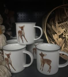 four white and brown deer mugs sitting on top of a table next to yarn