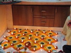 a woman sitting on the floor in front of a decorated diya with lit candles