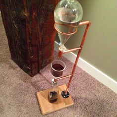 a glass filled with liquid sitting on top of a wooden stand next to a wall