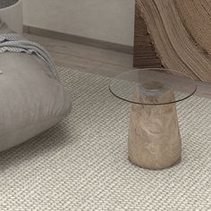 a glass table sitting on top of a rug next to a gray bean bag chair