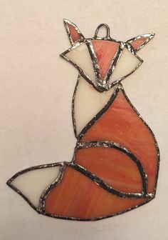 an orange and white stained glass ornament with a fox on it's back