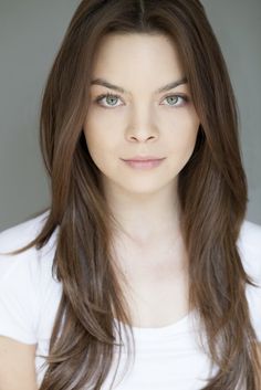 a woman with long brown hair is posing for the camera and looking at the camera