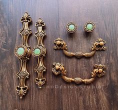 an assortment of ornate brass hardware on a wooden surface with green glass cabochons