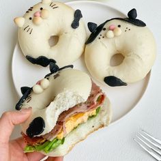 a person is holding a sandwich with donuts shaped like cats on it and one has an egg in the shape of a cat