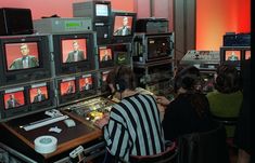 several people sitting in front of multiple televisions