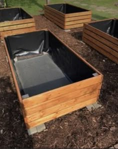 several wooden boxes are lined up on the ground in front of some grass and trees