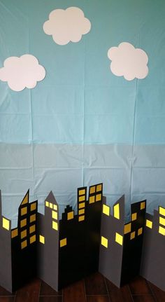 some paper cut out buildings and clouds in the sky