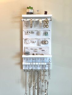 a white wall mounted jewelry rack with lots of necklaces