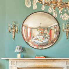 a fireplace with a mirror on the wall above it and a chandelier hanging from the ceiling