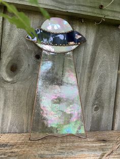 a metal object sitting on top of a wooden table next to a fence and tree