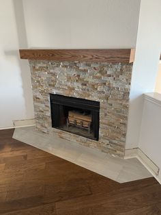 an empty room with a fire place in the middle and wood flooring on the other side