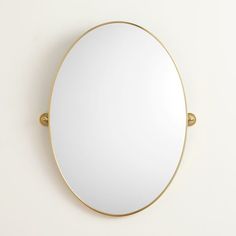 a round mirror mounted to the side of a wall with two brass fittings on it