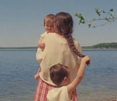 two young children standing on the shore of a lake with their arms around each other