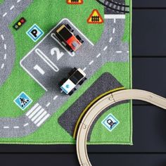 a play mat with cars and trucks on it next to a toy car race track