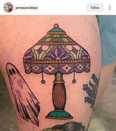 a woman's thigh with tattoos on it and a lamp in the middle of her leg