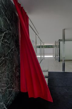 a red curtain hanging from the side of a wall next to a black and white floor