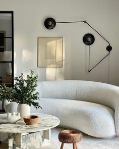 a living room with white furniture and plants