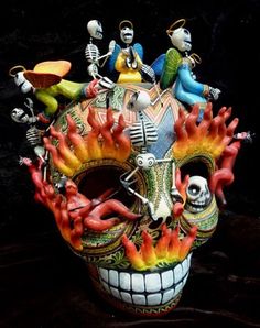 a colorful mask with many different figures on it's face and hands, sitting on a black surface