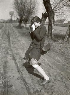 an old photo of a woman walking down a dirt road talking on a cell phone