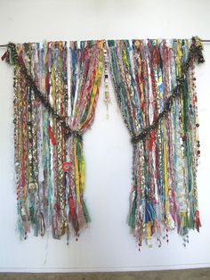 the curtains are covered with beads and other colorful things hanging from hooks on the wall