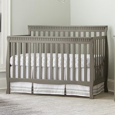 a baby crib with white and gray bedding