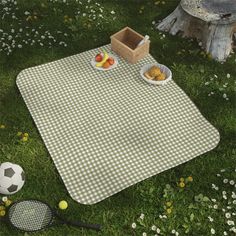 a picnic blanket with plates of food and tennis rackets on it in the grass