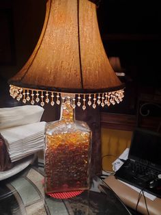 a lamp that is sitting on top of a table next to a glass bottle with liquid in it