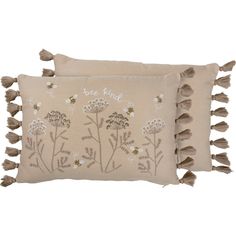 two embroidered pillows with tassels and flowers on the front, one in beige