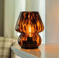 a glass candle holder sitting on top of a table