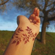 a person's arm with a tattoo on it and trees in the back ground