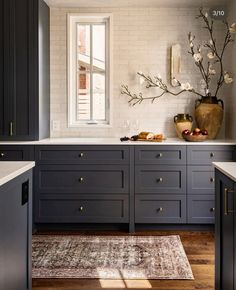 a kitchen with dark gray cabinets and white counter tops, along with a rug on the floor