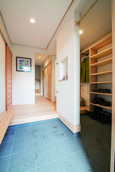 an empty room with wooden shelves and blue tile flooring in the foreground is a large open closet