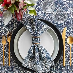 a place setting with blue and white plates, silverware and flowers on the table