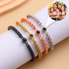 four different bracelets on top of a white napkin with an image of two people in the background