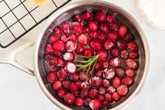 cranberry sauce in a pot with sugar on the rim and fresh rosemary sprigs