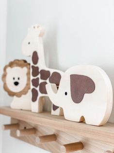 three wooden toy animals sitting on top of a shelf