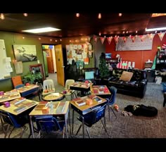 a room filled with lots of tables and chairs next to a wall covered in pictures