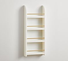 a white wall mounted shelf with gold bars on the top and bottom, against a white wall